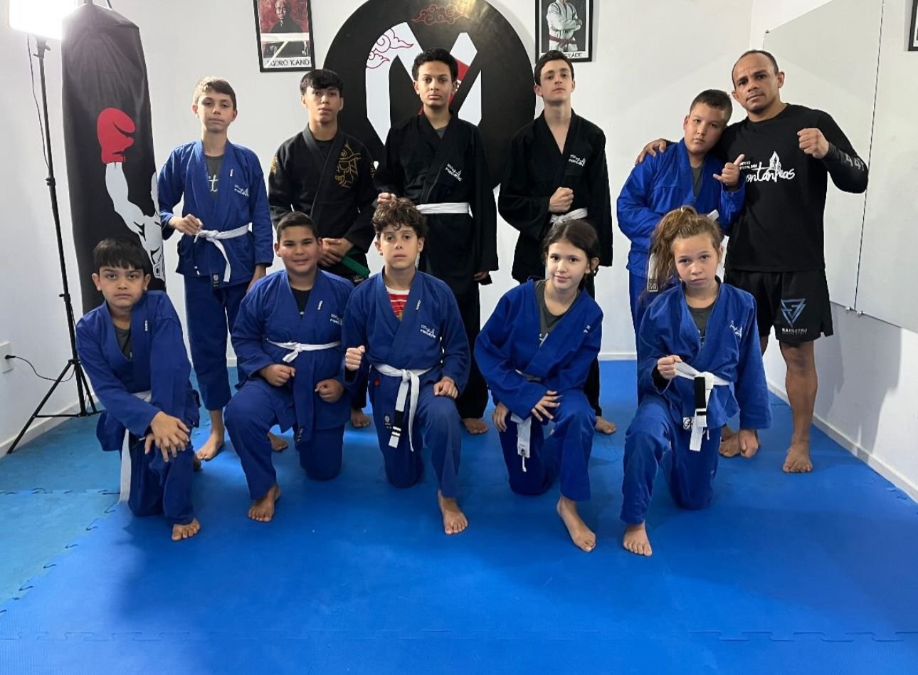 Turma de artes marciais com o professor no tatame do Centro de Treinamento